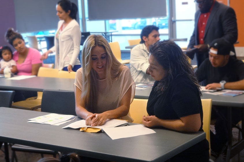 Students sitting at different tables receiving assistance.