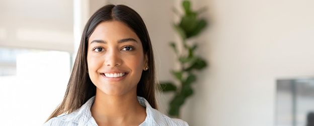 A person in an office setting smiles at the camera