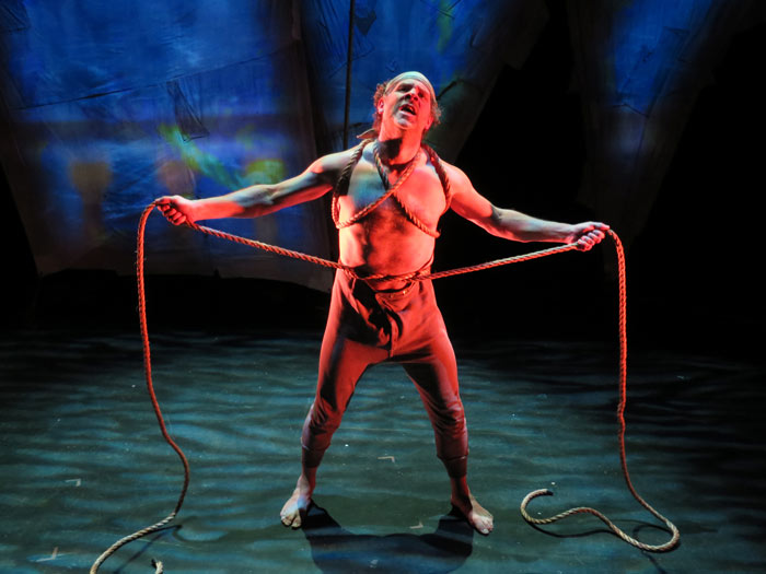 An actor stands in cloth pants while looking up emotionally.