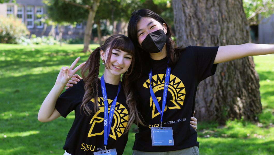 Two Writing Center team members posing on campus lawn and wearing team t-shirts